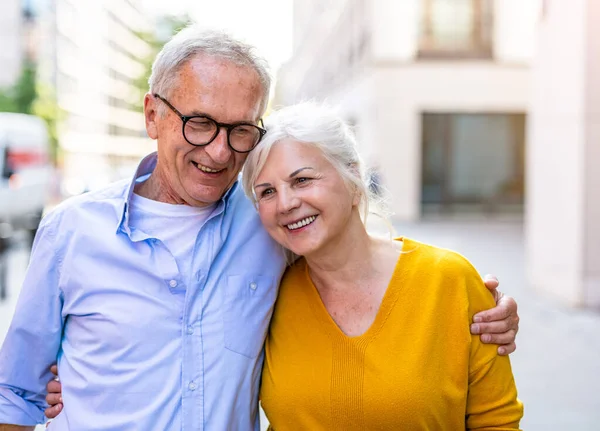 在城市里拥抱一对快乐的老夫妇的画像 免版税图库照片
