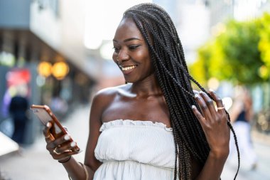 Şehirde cep telefonu kullanan genç bir kadının portresi.