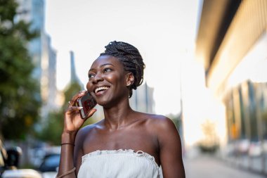 Şehirde cep telefonu kullanan genç bir kadının portresi.