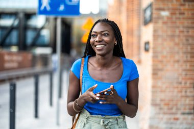 Şehirde cep telefonu kullanan genç bir kadının portresi.