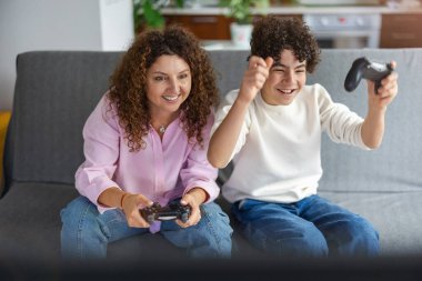 Anne ve oğlu evdeki kanepede otururken video oyunu oynuyorlar.