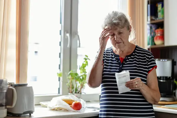 Senior woman going through her receipts at home after buying groceries