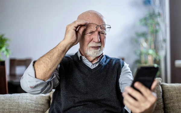 Senior man staring at his smartphone in confusion