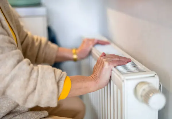 老太婆检查房间里的暖气散热器 — 图库照片
