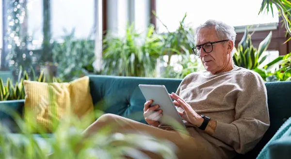 Hombre Mayor Usando Tableta Digital Mientras Está Sentado Sofá Sala Imagen De Stock