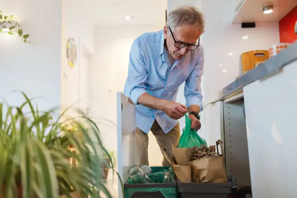Älterer Mann Sortiert Müll Wertstofftonne Hause lizenzfreie Stockfotos