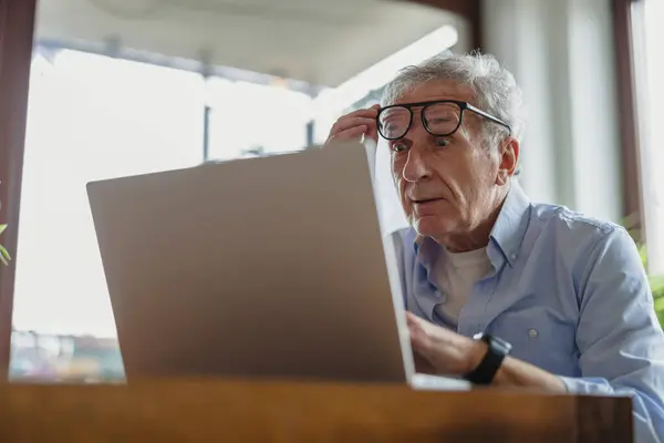 Пожилой Мужчина Пользуется Ноутбуком Дома Стоковое Фото