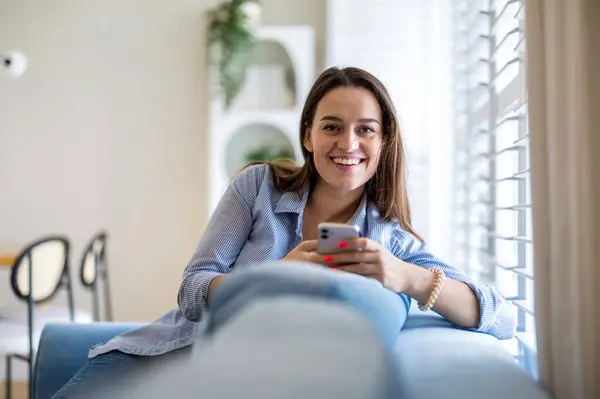 Glimlachende Vrouw Met Mobiele Telefoon Bank Woonkamer Thuis Rechtenvrije Stockafbeeldingen