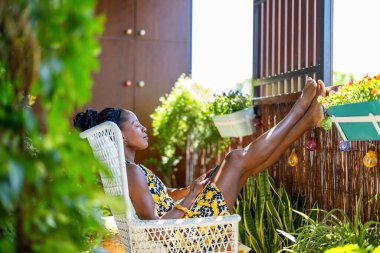 Evde balkonda dinlenirken cep telefonu kullanan güzel bir kadın.