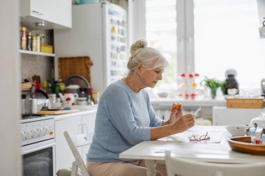 Son sınıf öğrencisi kadın mutfağında hap içiyor.