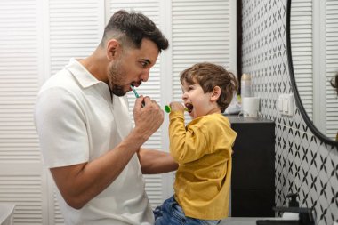 Baba ve oğul banyoda birlikte diş fırçalıyorlar.