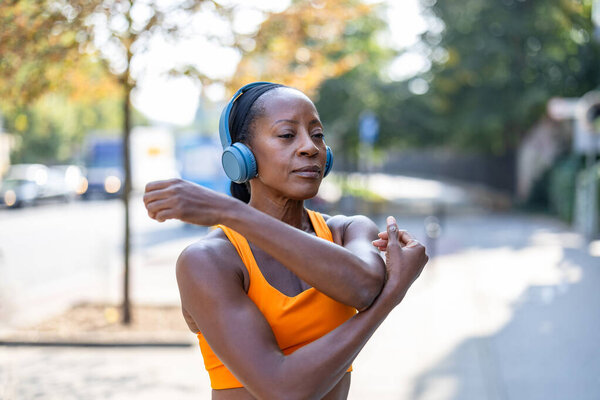Happy woman listening to music with headphones while exercising in the city