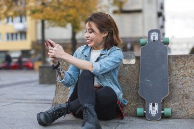 Şehirde kaykaylı gülümseyen genç bir kadının portresi.