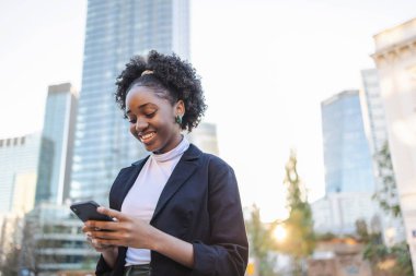 Şehirde cep telefonu kullanan genç bir kadının portresi