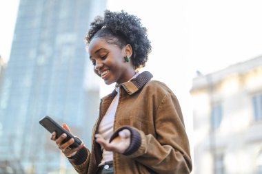 Şehirde cep telefonu kullanan genç bir kadının portresi