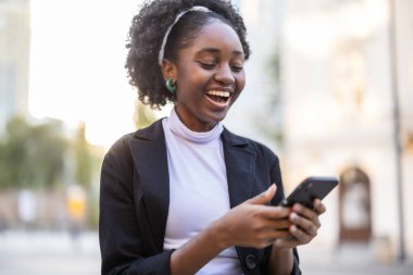 Şehirde cep telefonu kullanan genç bir kadının portresi