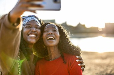 Şehir plajında cep telefonu kullanan gülümseyen kadınlar