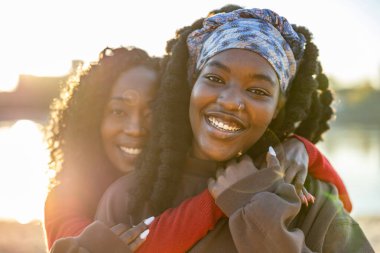 Şehir plajında gülümseyen ve kucaklaşan iki kadının portresi.
