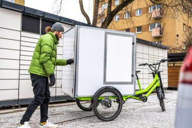 Bisikletli kurye şehirde kargo motosikletiyle paket teslimatı yapıyor.