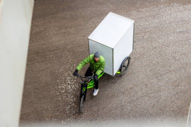 Bisikletli kurye şehirde kargo motosikletiyle paket teslimatı yapıyor.