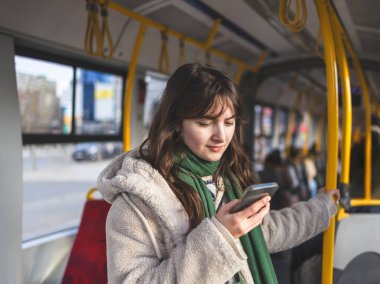 Tramvayda telefonunu kullanan genç bir kadın.