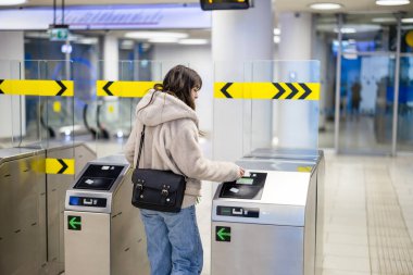 Metrodaki turnikelerden geçen genç bir kadın.