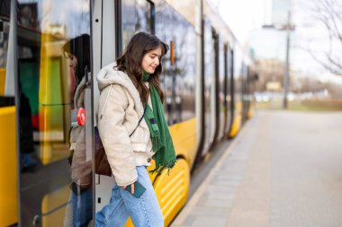 Şehirde bir durakta tramvaydan inen genç kadın.