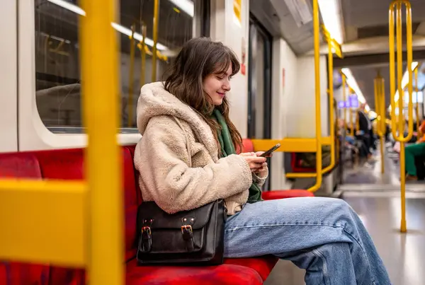 Metrodayken telefonunu kullanan genç bir kadın.