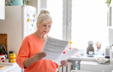 Evdeki mali belgelere bakan kıdemli bir kadın. 
