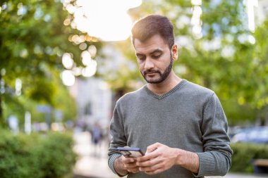 Şehirde cep telefonunu kullanan genç bir adamın portresi.