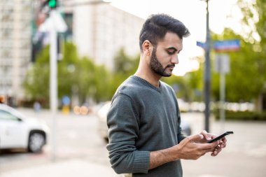Şehirde cep telefonunu kullanan genç bir adamın portresi.