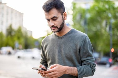 Şehirde cep telefonunu kullanan genç bir adamın portresi.