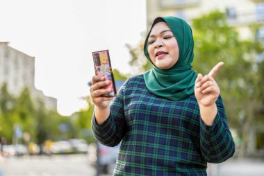 Şehirde cep telefonuyla video görüşmesi yapan Müslüman bir kadın.