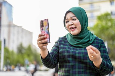 Şehirde cep telefonuyla video görüşmesi yapan Müslüman bir kadın.