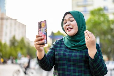 Şehirde cep telefonuyla video görüşmesi yapan Müslüman bir kadın.