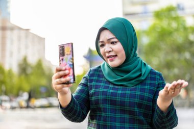 Şehirde cep telefonuyla video görüşmesi yapan Müslüman bir kadın.