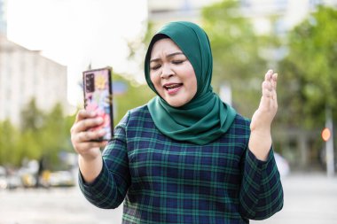 Şehirde cep telefonuyla video görüşmesi yapan Müslüman bir kadın.