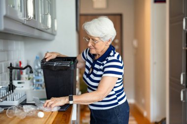 Üst düzey kadın evdeki mutfakta plastik geri dönüşümü yapıyor.