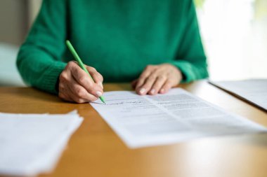 Tanımlanamayan üst düzey kadın bir belge imzalıyor, yakın plan.