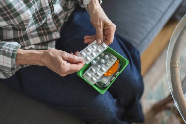 Tanımlanamayan yaşlı kadın ilaçlarını evde alıyor, kadın eli yakın.