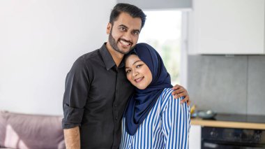 Mutfakta duran mutlu Müslüman bir çiftin portresi.