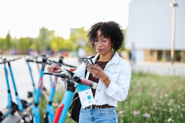 Akıllı telefondan elektrikli scooter çalıştıran kadın 