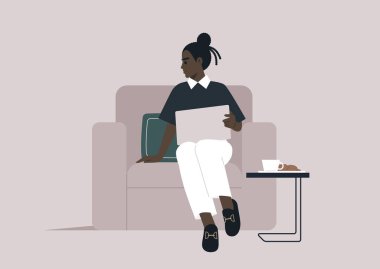 Genç ve kendinden emin bir kadın rahat bir şekilde koltukta oturur, günlük aktivitelerine dalmış, dizüstü bilgisayarı açık ve elinin altında.