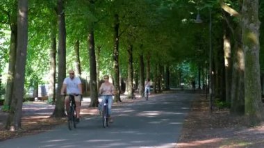 Şehir merkezindeki gölgeli ağaçların arasında bir sürü bisikletçi geziniyor. Zaman aşımı.