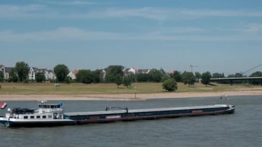 Almanya, DÜZSELDORF, 2022 dolayları. Kargo gemisi, mavna rıhtım boyunca Kuzey Ren Nehri 'ne gidiyor. Su altyapısı ile nakliye.