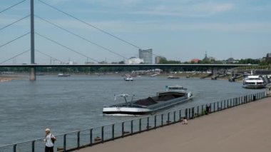 Almanya, DÜZSELDORF, 2022 dolayları. Kargo gemisi, kömür taşıyan bir mavna rıhtım boyunca Kuzey Ren Nehri boyunca gider. Su altyapısı ile nakliye.