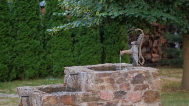 Eski dökme demir bir el pompası arka bahçedeki dekoratif bir şelale çeşmesi için donatılmıştır..