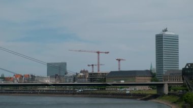 Köprüde, Dusseldorf 'un merkezindeki rıhtımın arka planına karşı hareket eden arabalar..