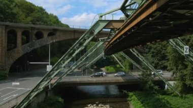 Almanya, Wuppertal, 2022 civarı. Wuppertal Askılık Demiryolu. At arabası arka planda eski taş demiryolu yüksek köprüsünde ilerliyor..