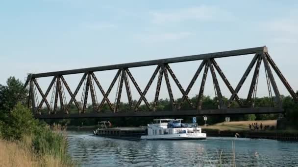 ドイツ ルーディンハウヘン Circa 2022 古い錆びた鉄道橋の下の水路を船が航行する — ストック動画